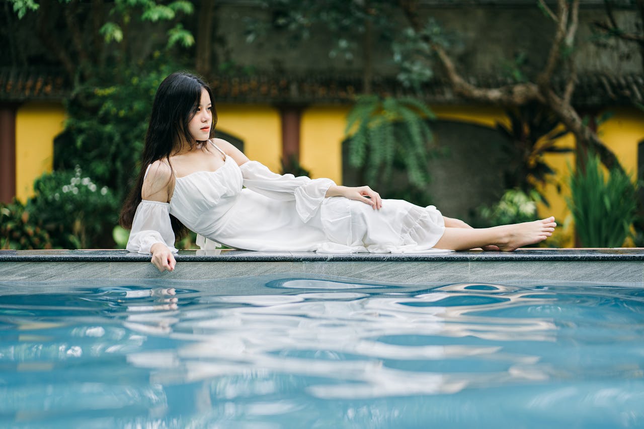 Attractive Asian woman lying on edge of pool